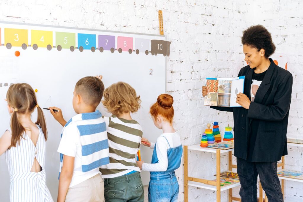 Children actively participating in classroom learning with a teacher guiding them.