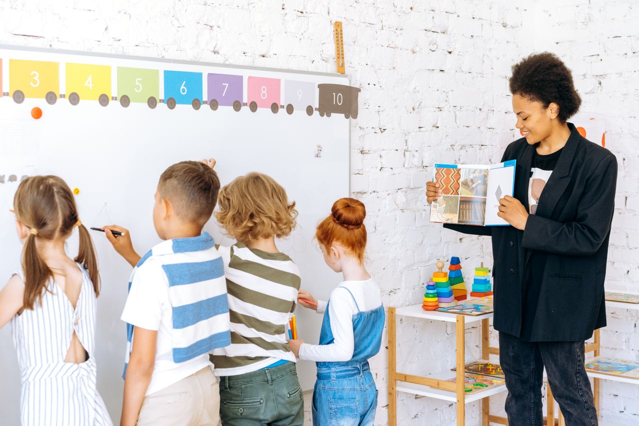 Home Children actively participating in classroom learning with a teacher guiding them.