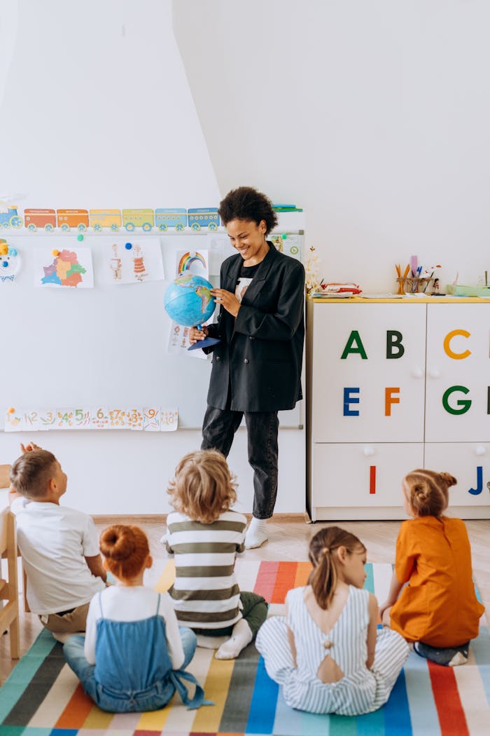 Home A teacher engaging preschool children with a globe in a classroom setting.